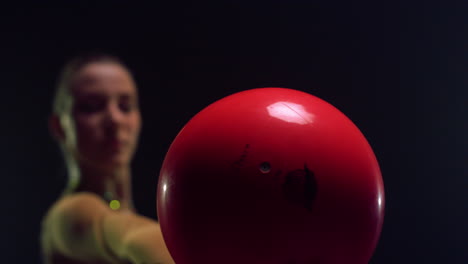 young woman doing calisthenics indoors. gymnast rolling ball on hand inside.