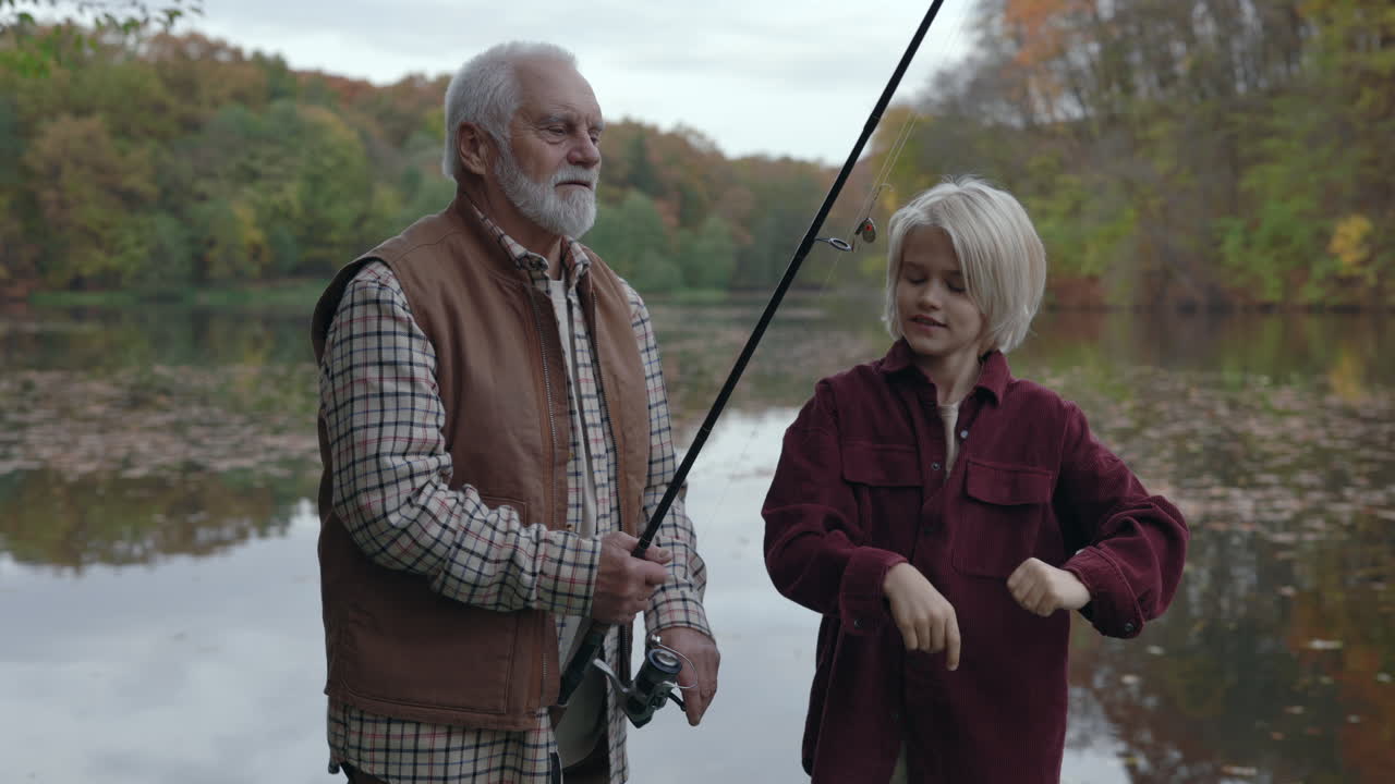 Grandfather and Grandson Fishing by a Lake in Autumn