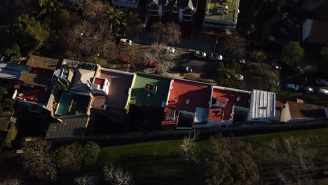 roofs on a house of different colors, cars drive along the road near the house, a residential area and a park