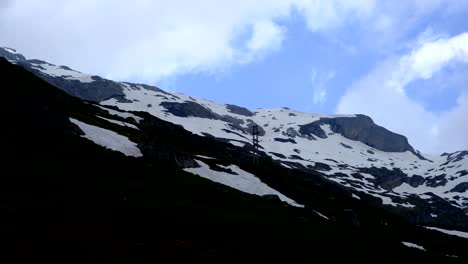 A-mountain-with-disappearing-snow-and-a-cloudy-sky-at-Klausenpass-Mountain-of-Switzerland