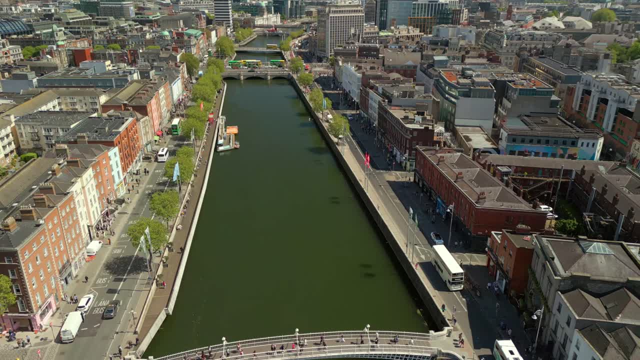 Wide, front-on reversing aerial video of the River Liffey, various bridges and Dublin City Centre in Dublin, Ireland on a bright and sunny day. Filmed in 4K, 60FPS and with Rec709 color.