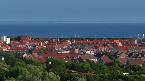 aerial view of charming old windmill amidst red roof houses of zoutelande, netherlands