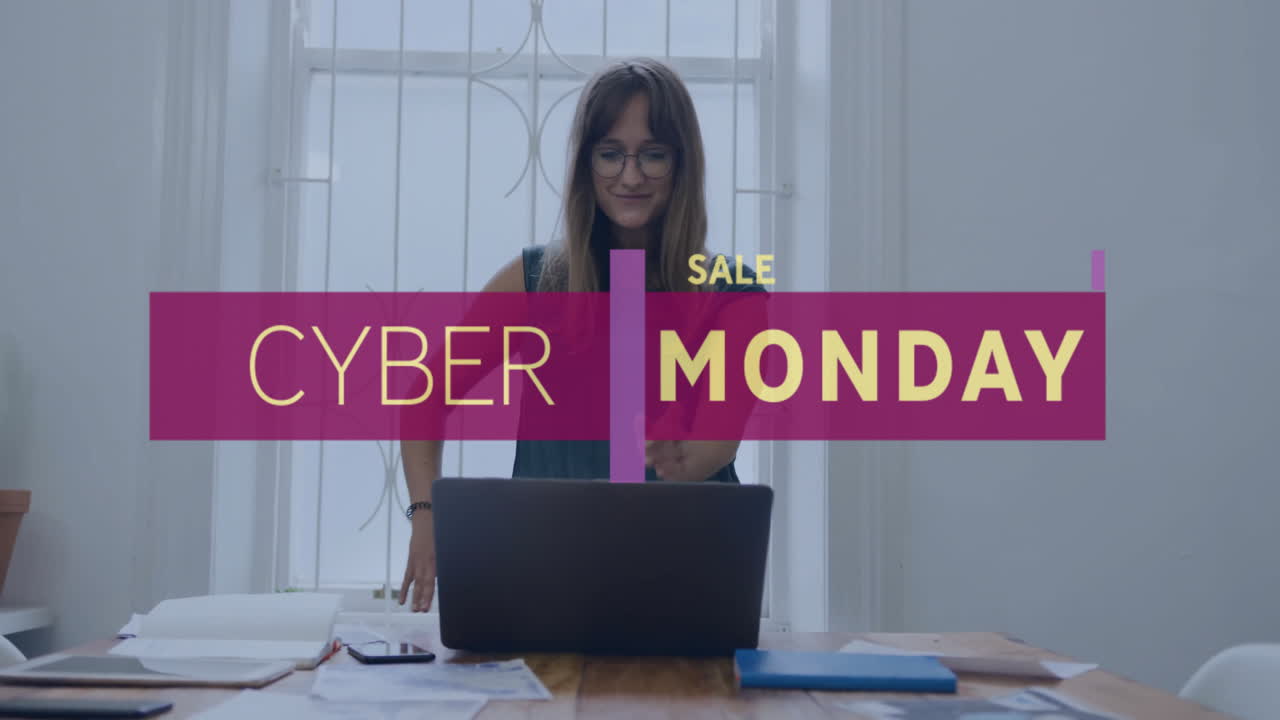 Animation of cyber monday text over caucasian businesswoman using laptop in office