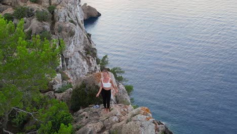 increíble vista aérea de arriba vuelo ibiza acantilado yoga árbol pose modelo chica puesta de sol por la noche