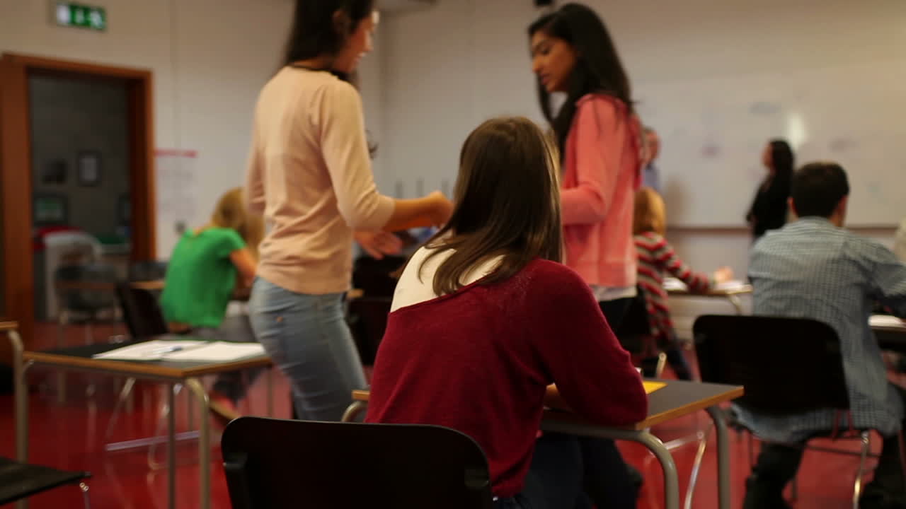 estudiantes intercambiando asientos durante la clase