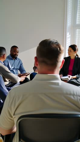 a group of people are sitting in chairs and talking to each other