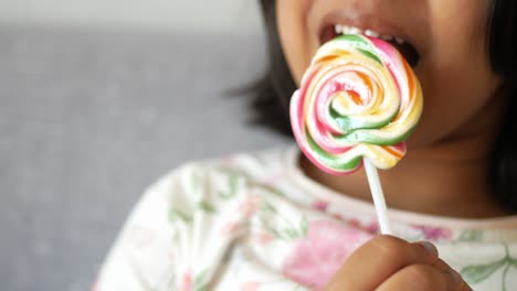 girl eating a colorful lollipop