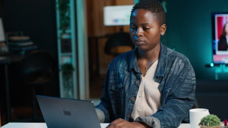 woman working on laptop in a home office at night