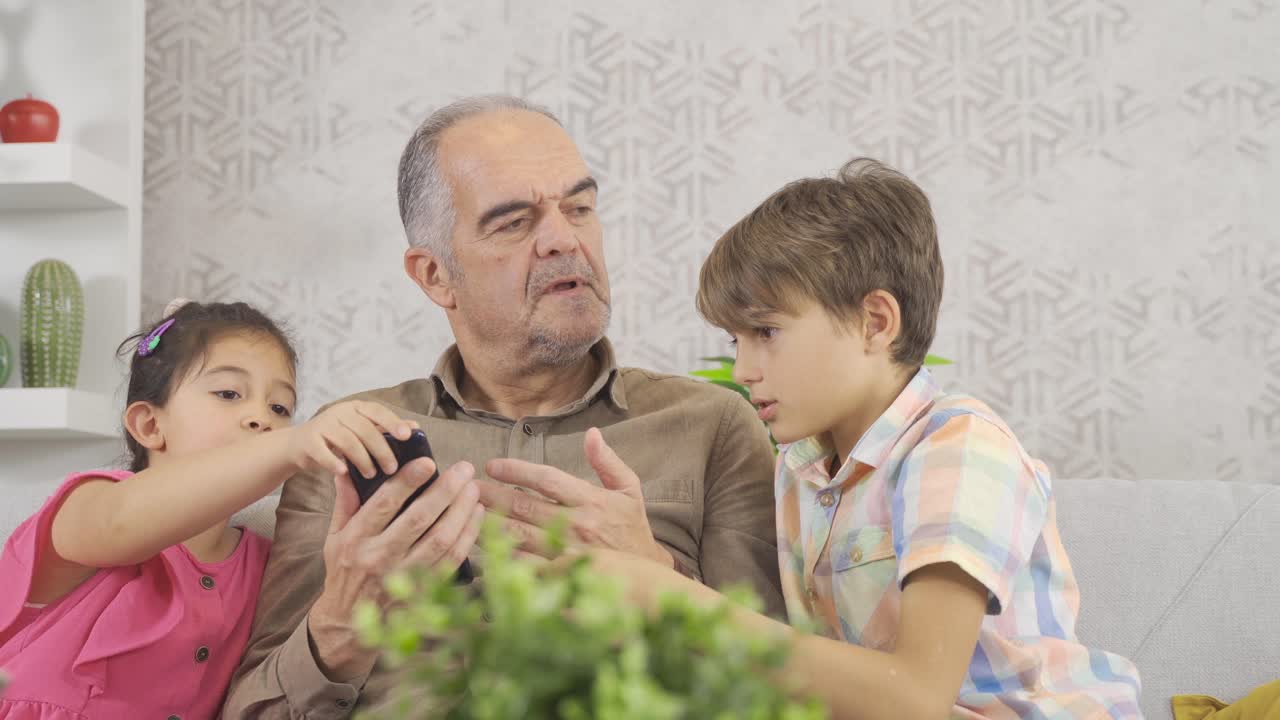 el viejo está aprendiendo a usar el teléfono inteligente para los niños.