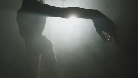 modern ballet performance. silhouette of graceful ballerina dancing mysterious dance in textured smoke in spotlight