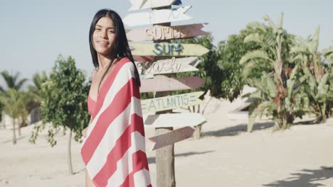 happy hispanic woman dancing with american flag by signpost on sunny beach, slow motion