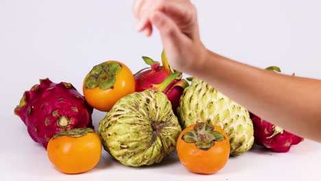 a hand selects fruit from a colorful assortment