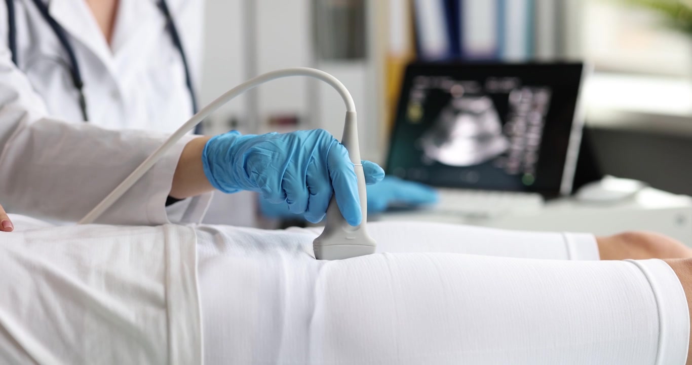 Mano del medico con sonda scansiona gli organi pelvici di una donna in clinica.