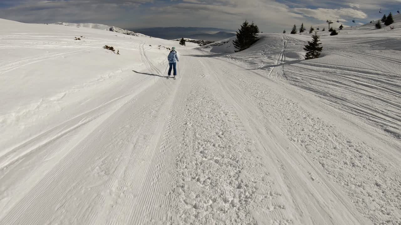 Point of view to a girl skiing on a narrow slope on a sunny day.