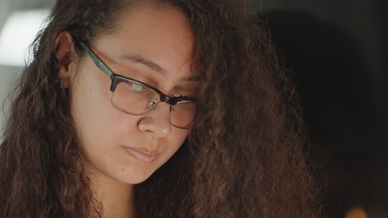 Donna pensierosa che si riposa vicino a una fonte di luce. Donna tranquilla che riflette in silenzio mentre è seduta in un ambiente accogliente. Individuo femminile sereno che contempla la vita comodamente seduto vicino a una luce soffusa.