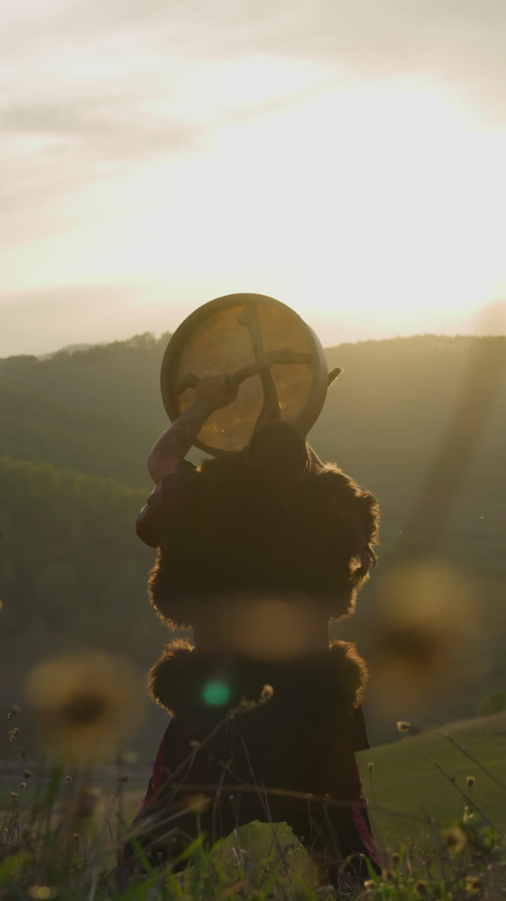 Altai man plays shaman drum among green highland backside view slow motion. Thanking land gods for protection. Religious ceremony and traditional music