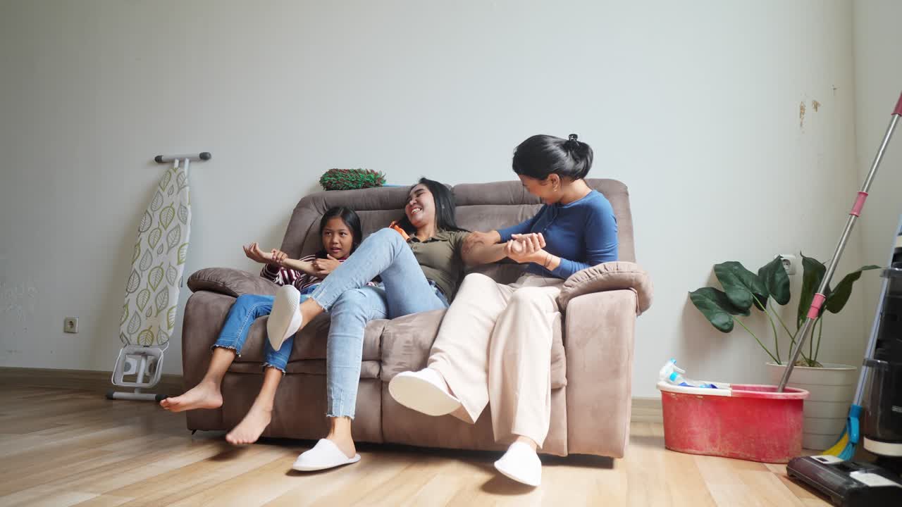 Happy Asian Mother Enjoying Massage By Her Daughters After Clean The House