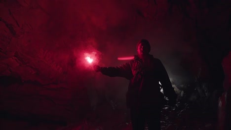 man with red flare in a cave