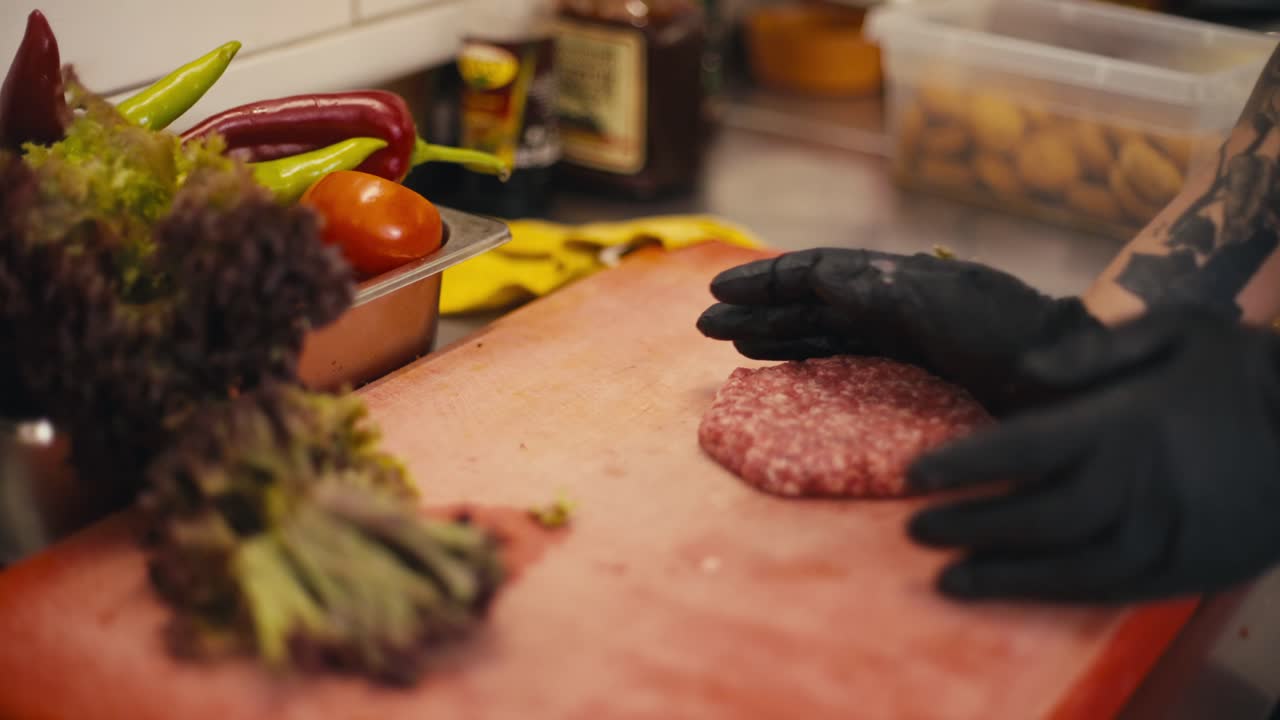 Chef de luvas tempera um hambúrguer, close-up das mãos numa bancada de cozinha vibrante