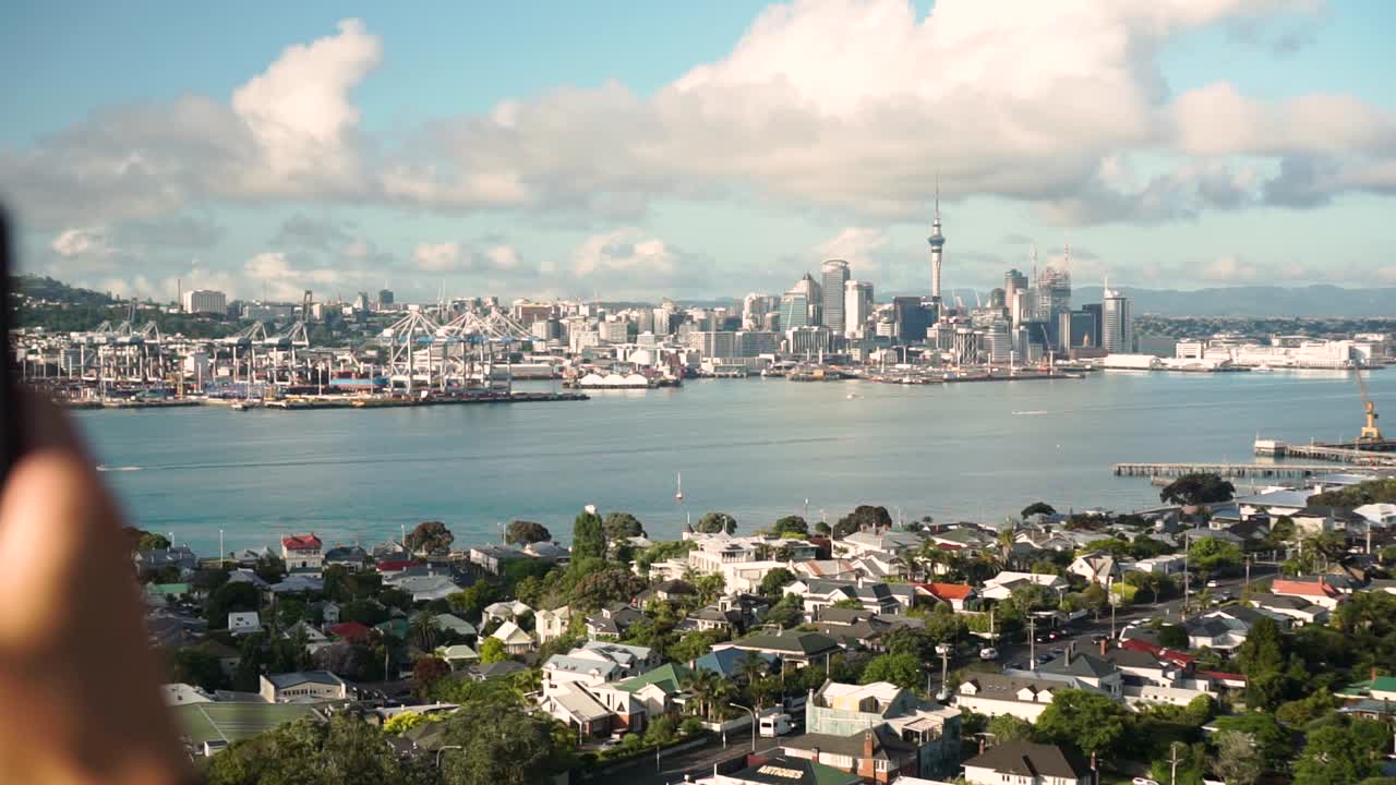 SLOWMO - Close up of caucasian man taking photo and refocus on Auckland skyline, New Zealand