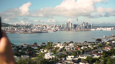slowmo - close up of caucasian man taking photo and refocus on auckland skyline, new zealand