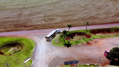 Drone-View-of-truck-getting-on-the-road-from-a-farm,-field-harvested