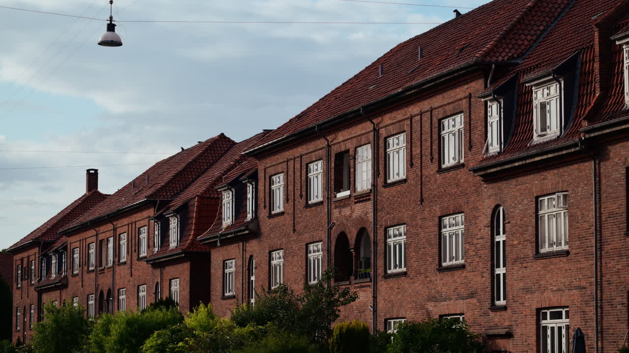 Building facade featuring red brick walls and many windows under a cloudy sky. Copenhagen, Denmark