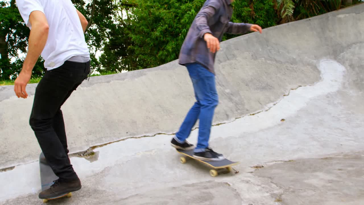 sección baja de hombres jóvenes practicando patinaje en la rampa en el parque de patinaje 4k