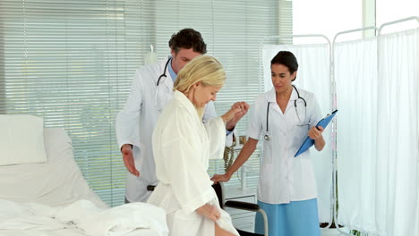 doctors helping patient to sit on wheelchair