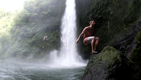 slow motion shot of a man doing a backflip into the water at nungnung waterfall in bali, indonesia