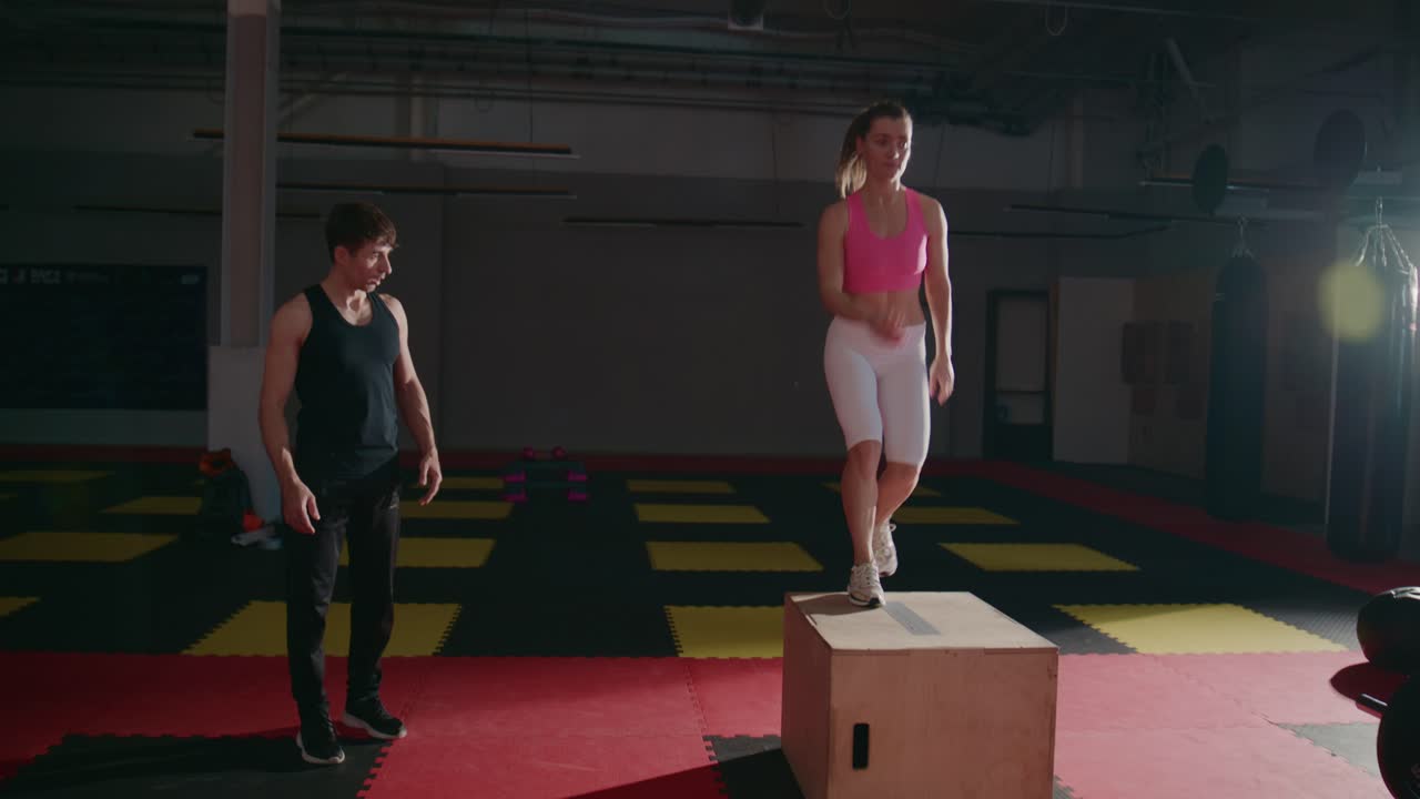 Young Woman Performing Box Step-Ups with Trainer in Gym