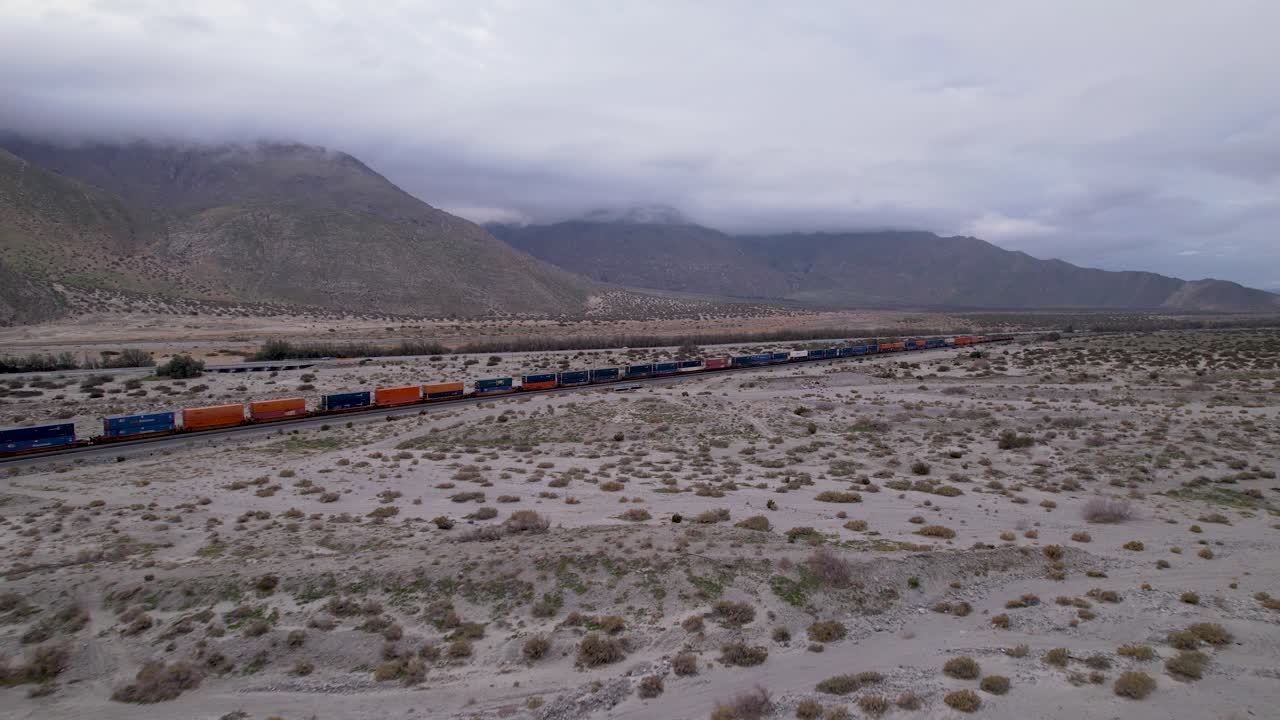imágenes aéreas de drones del tren de carga en el desierto de palm springs con montañas en el fondo, tiro lento hacia adelante