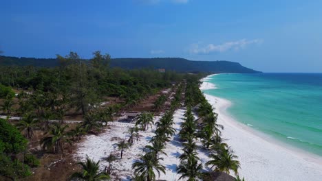 sok san beach with turquoise water washing the white sand, surrounded by palm trees and tropical vegetation. unique aerial view flight dolly left drone