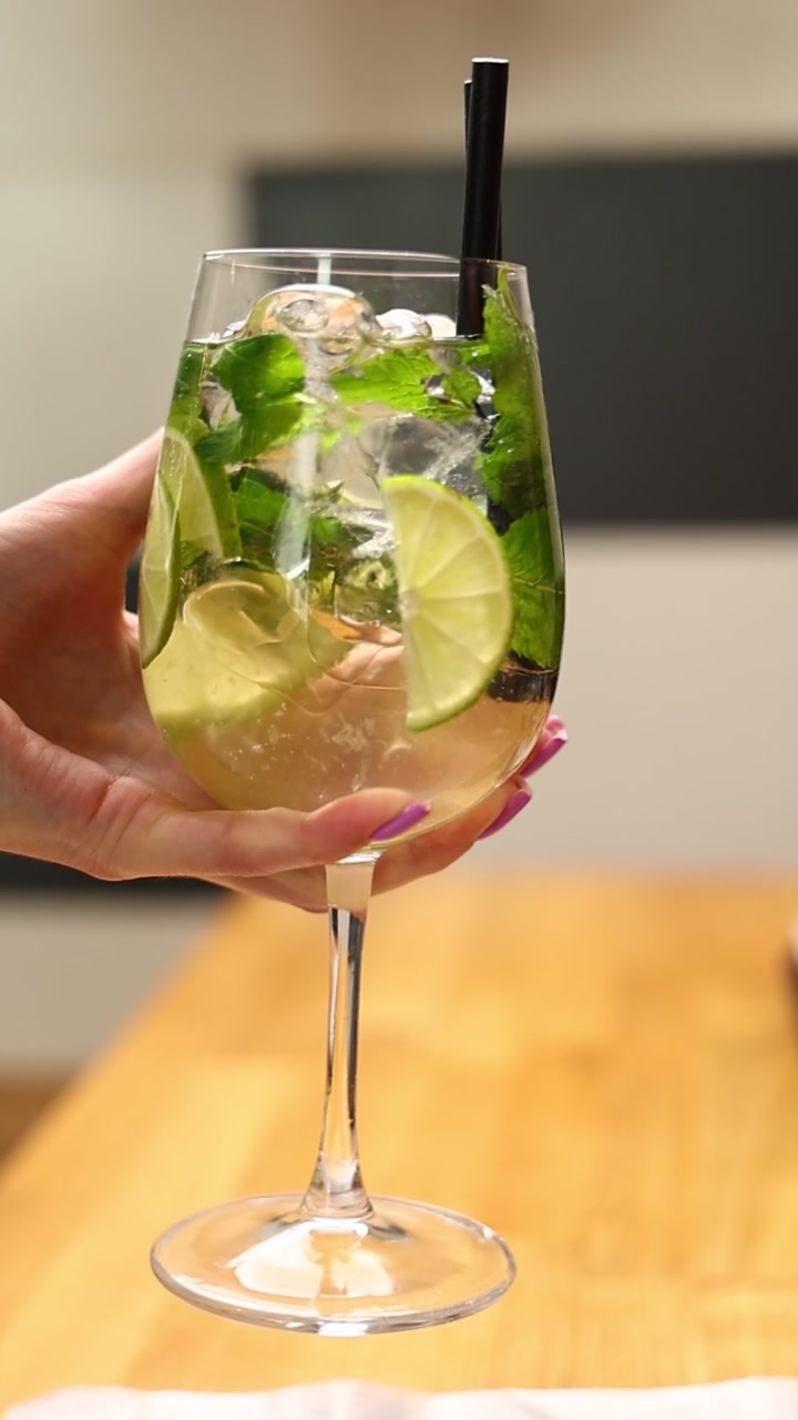Mano che tiene un rinfrescante cocktail Mojito con lime e menta