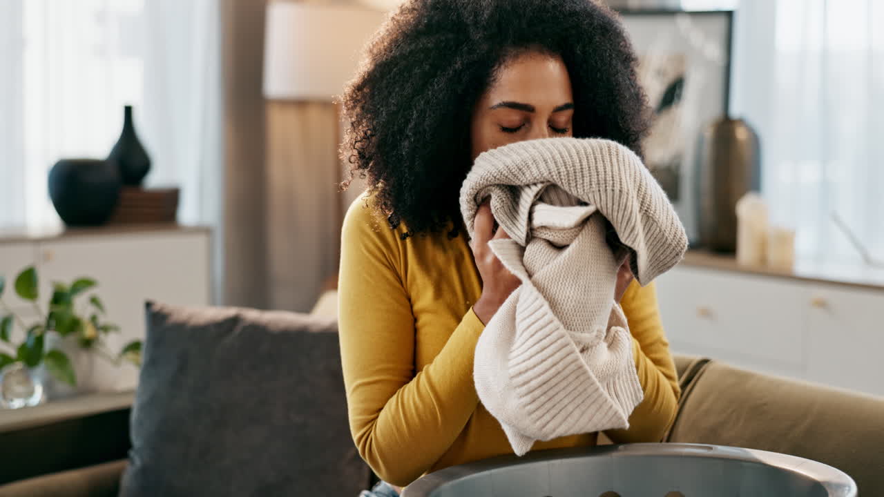 Woman smelling clean laundry at home