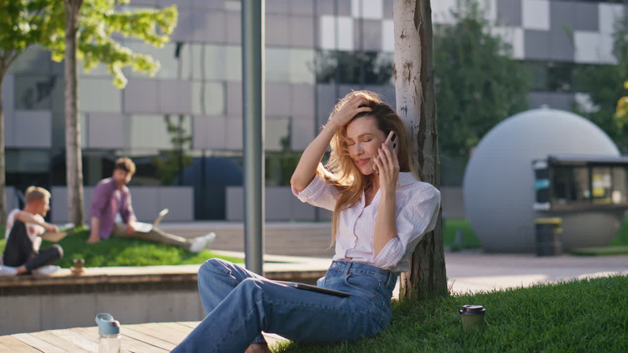 미소 짓는 소녀가 공원에서 친구와 스마트폰을 통신하고 있습니다. 예쁜 여자가 휴식을 취하고 있습니다.