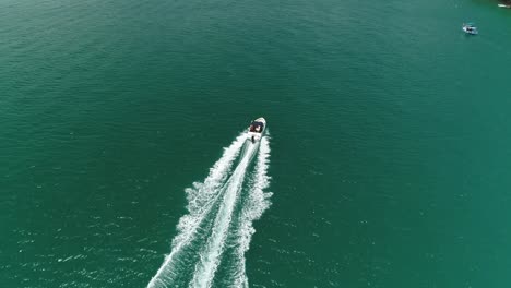 drone aereo sparato raggiungendo il motoscafo e seguendo da dietro in un mare calmo turchese