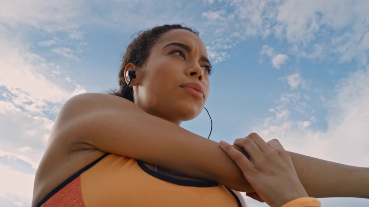 Jovem Mulher Alongando os Braços ao Ar Livre Contra o Céu Azul