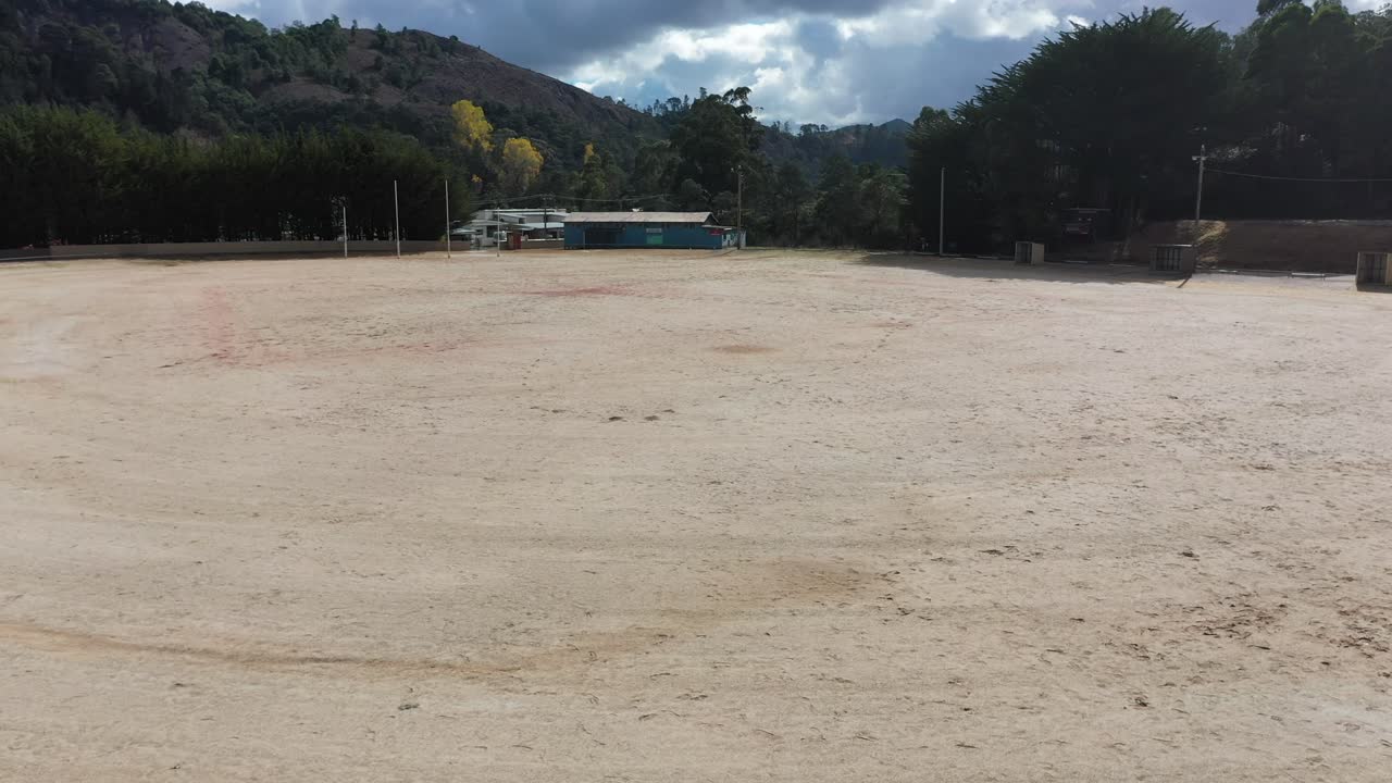 Slow pan around goal posts to reveal ground and mountains in rear - aerial drone shot Queenstown Oval, Tasmania, Australia - famous gravel oval