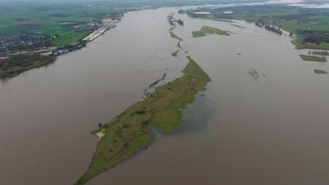 Vista-Aérea-Del-Rover-Waal-Después-De-Que-Se-Haya-Desbordado-Cerca-De-Gorinchem,-En-Las-Afueras-De-Rotterdam,-Con-Granjas-Y-Comunidades-Locales-Afectadas-Por-Inundaciones-Devastadoras.