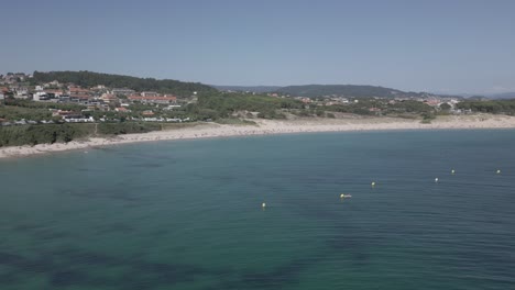 raw footage of beachfront village with emerald water and forest