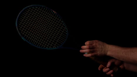 hand spinning a tennis racket on black background