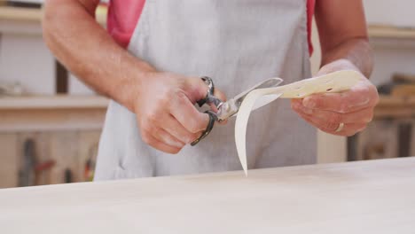 fabricante de tablas de surf masculino caucásico con una máscara facial y preparándose para pulir una tabla de surf