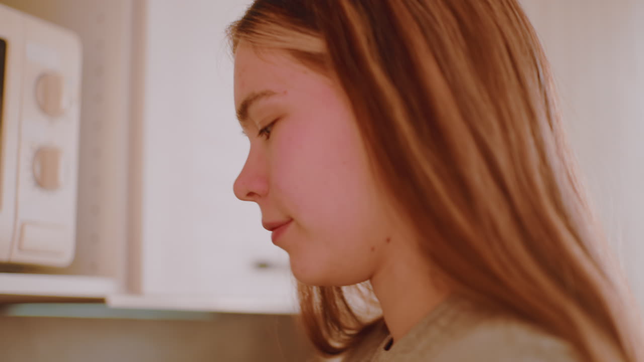 Close up of girl collecting coffee container from top cabinet in kitchen, preparing morning tea with calm motion as sunlight filters through window, beginning daily routine