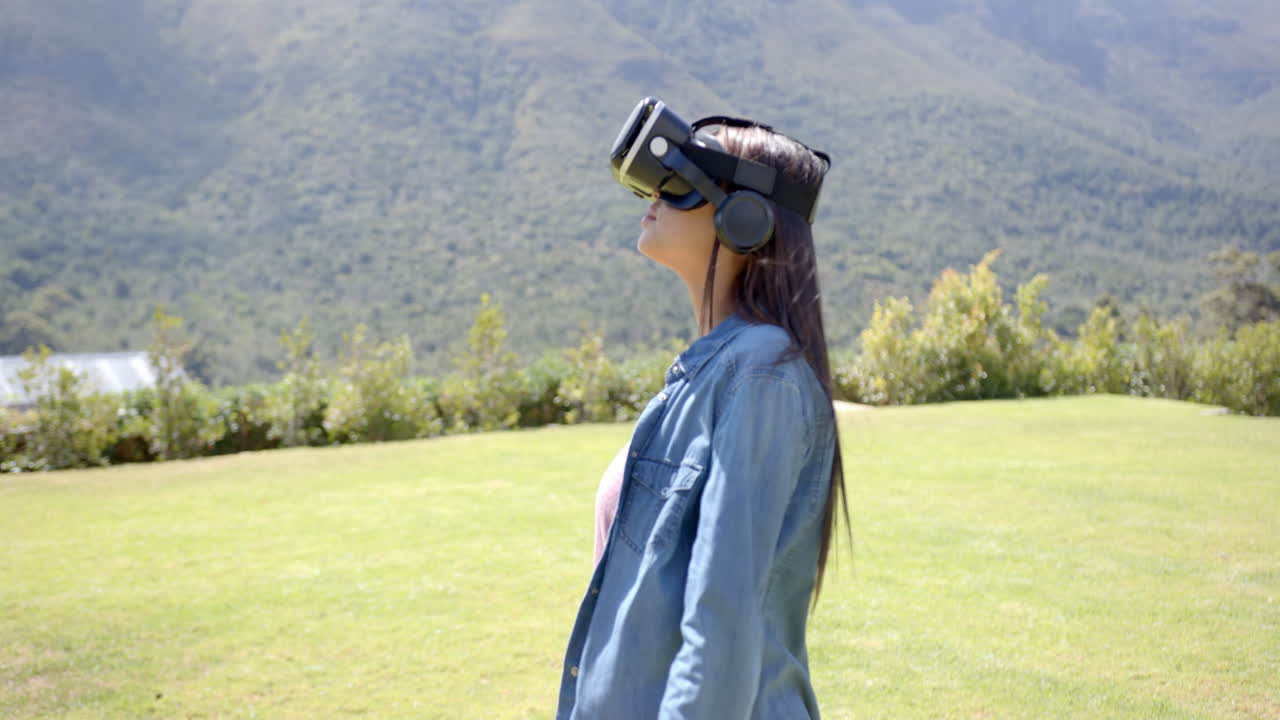 Ung kvinde af blandet etnicitet iført virtual reality-headset udendørs.