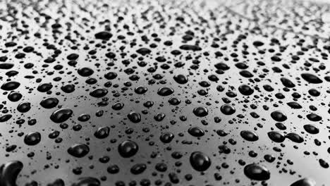gotas de lluvia en una superficie brillante del coche, tiempo nublado, reflexión, textura, efecto anti lluvia