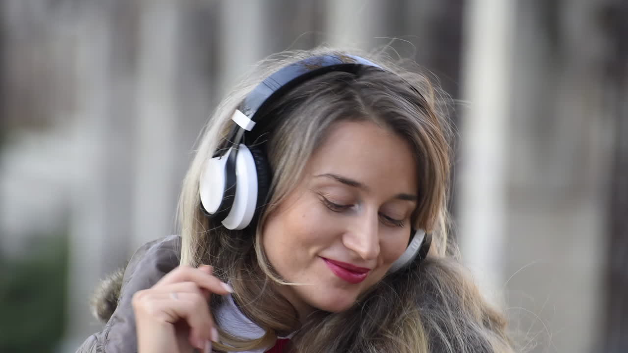 Woman listening to music in her headphones while singing along and dancing in the street