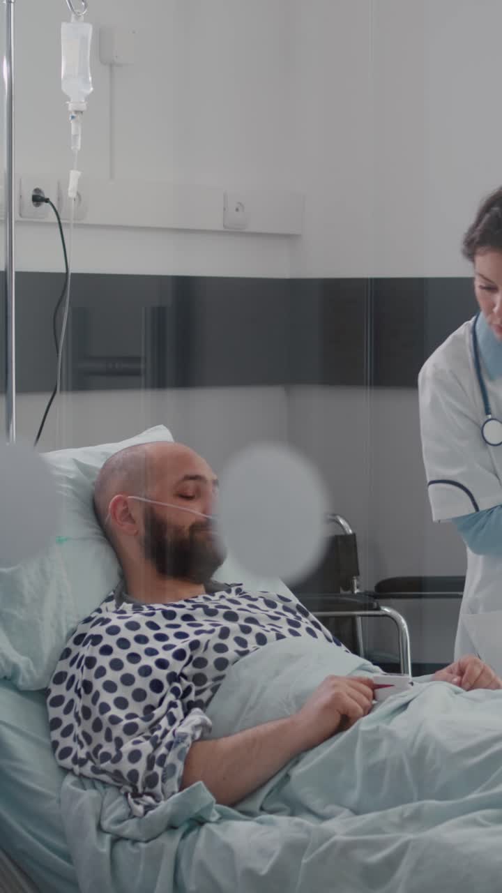 Vertical video: Patient sitting in bed having respiratory illness while medical nurse monitoring heart pulse