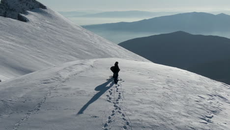 Two-snowboarders-preparing-and-ready-to-set-off-down-slopes-of-tall-snow-covered-mountain-in-the-alps