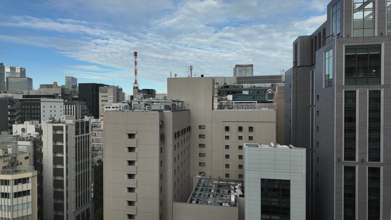 Time-lapse estático dos telhados dos edifícios de Ginza, destacando o design urbano de Tóquio contra um céu dinâmico